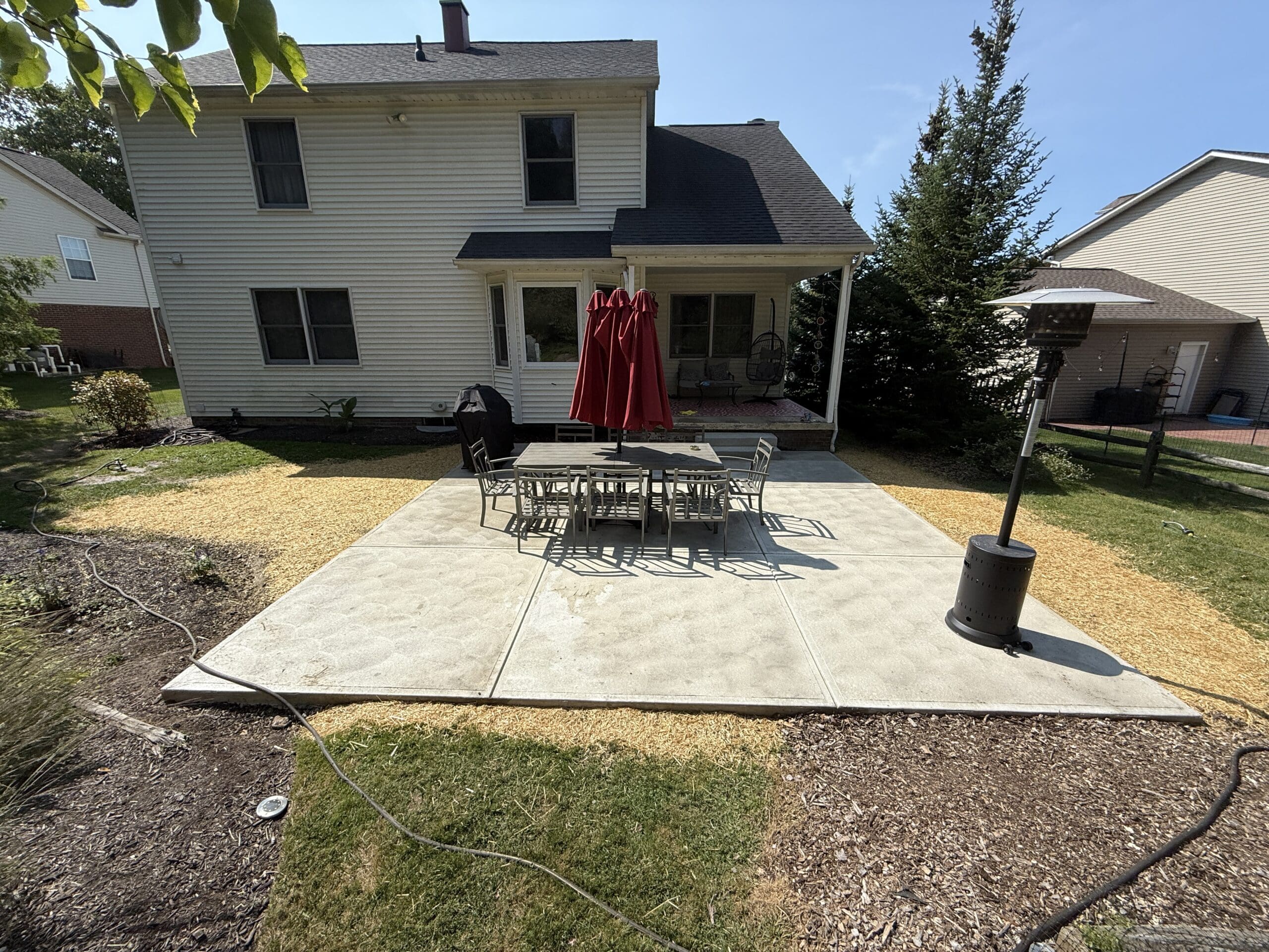 In the backyard of a home near a patio, pro finish has freshly trimmed and mulched a yard.
